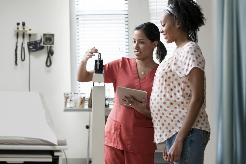 Pregnant woman getting weighed at doctor's office