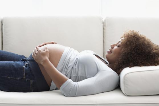 Pregnant woman lying on back and feeling stomach